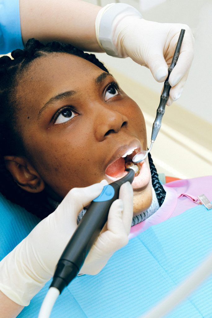 Black woman receiving a dental check-up by a professional dentist in a clinic.