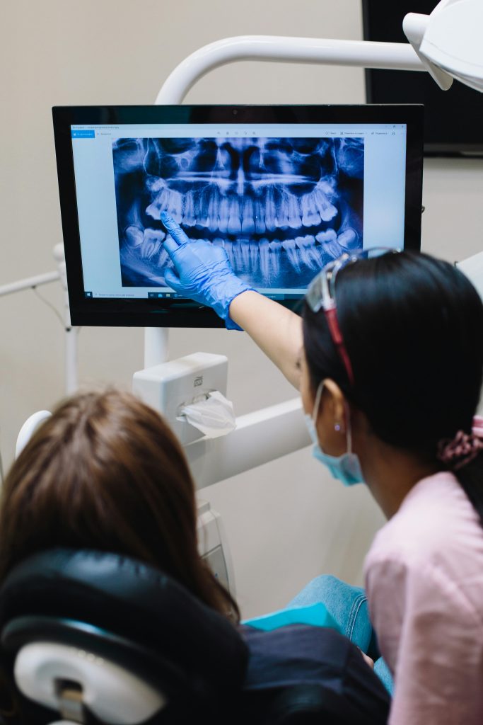 Dentist examines dental x-ray with patient in modern clinic setting.